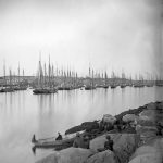 Schooner fleet anchored in the inner harbor. Looking east from Rocky Neck, Duncan's Point wharves and Lane house (far left), Sawyer School cupola on Friend St. 1870s. Acc.# 2013.068
